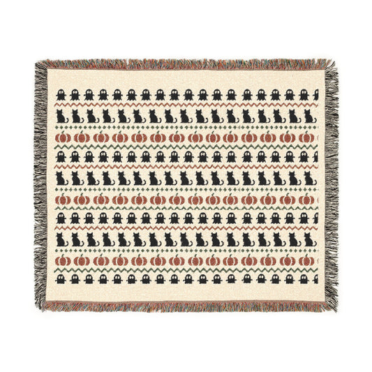 Fair Isle Halloween throw blanket draped on a sofa in neutral bone, charcoal and rust