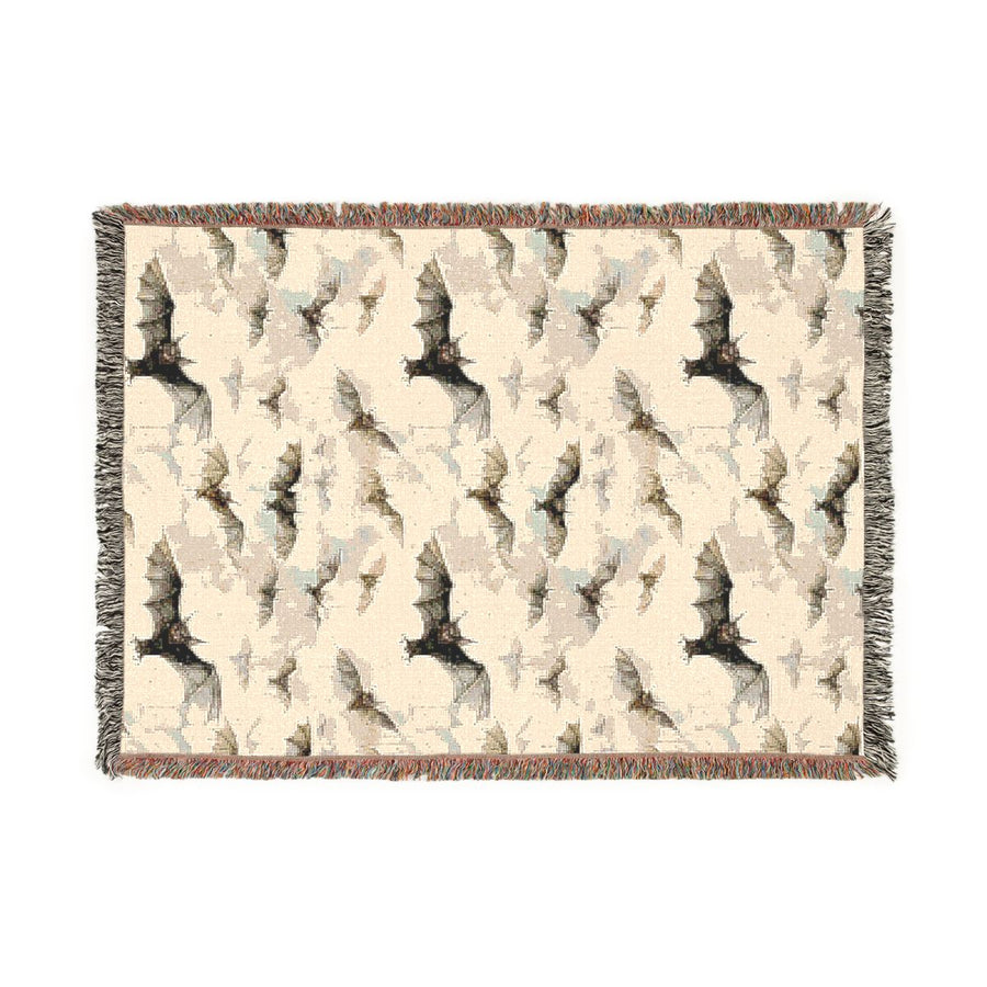 Bat woven blanket laid flat, cream cotton jacquard with a pattern of black bats and fringed edges