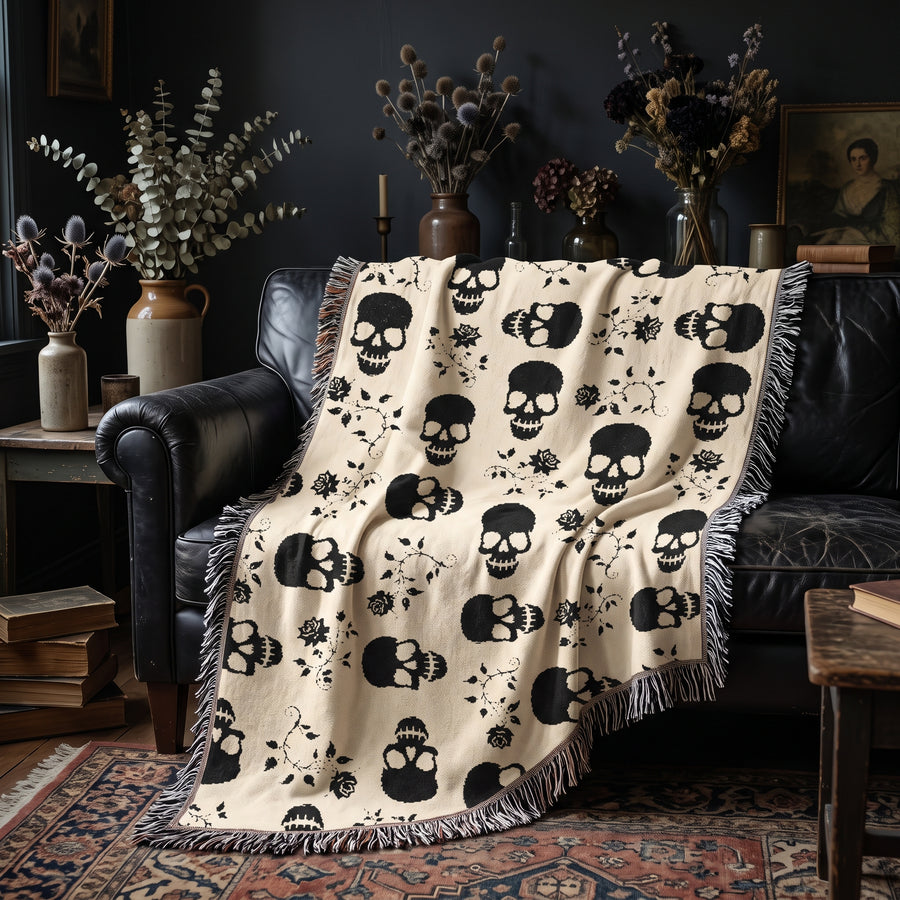 Black skull woven blanket draped over a black leather sofa in a moody living room