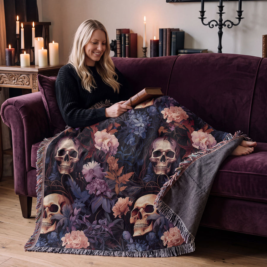 Woman reading on a velvet sofa under the skull and flowers woven blanket