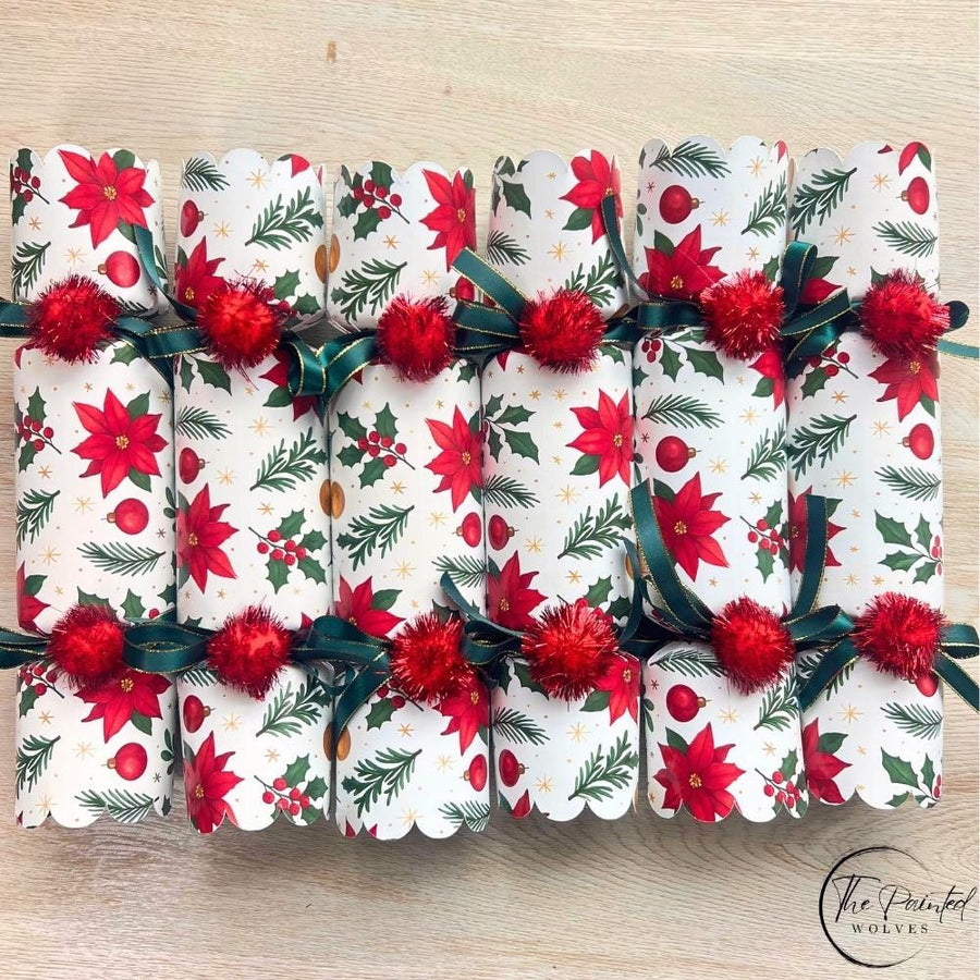 Six red poinsettia Christmas crackers in a row with green ribbon and red pom poms