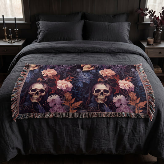 Questionably Cute skull and flowers woven blanket folded across the foot of a queen bed with charcoal linen