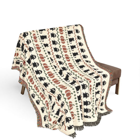 Haunted Heirloom woven blanket draped over a chair, showing the ghost and black cat pattern