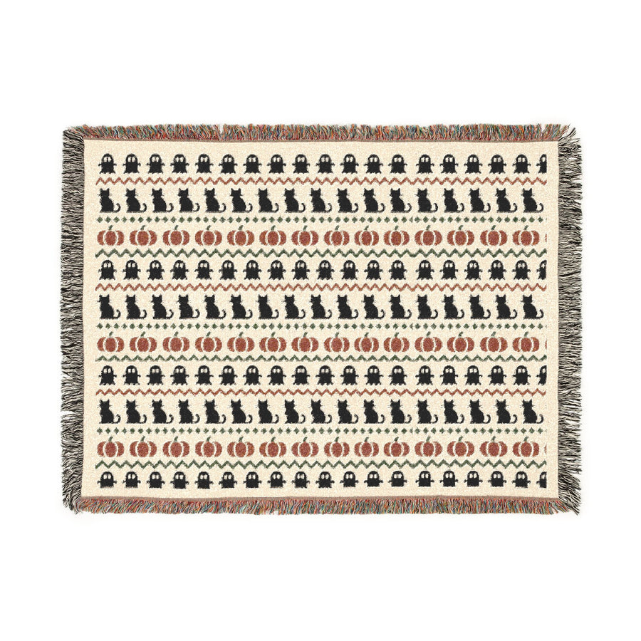 Halloween woven blanket draped over a chair in bone and rust tones