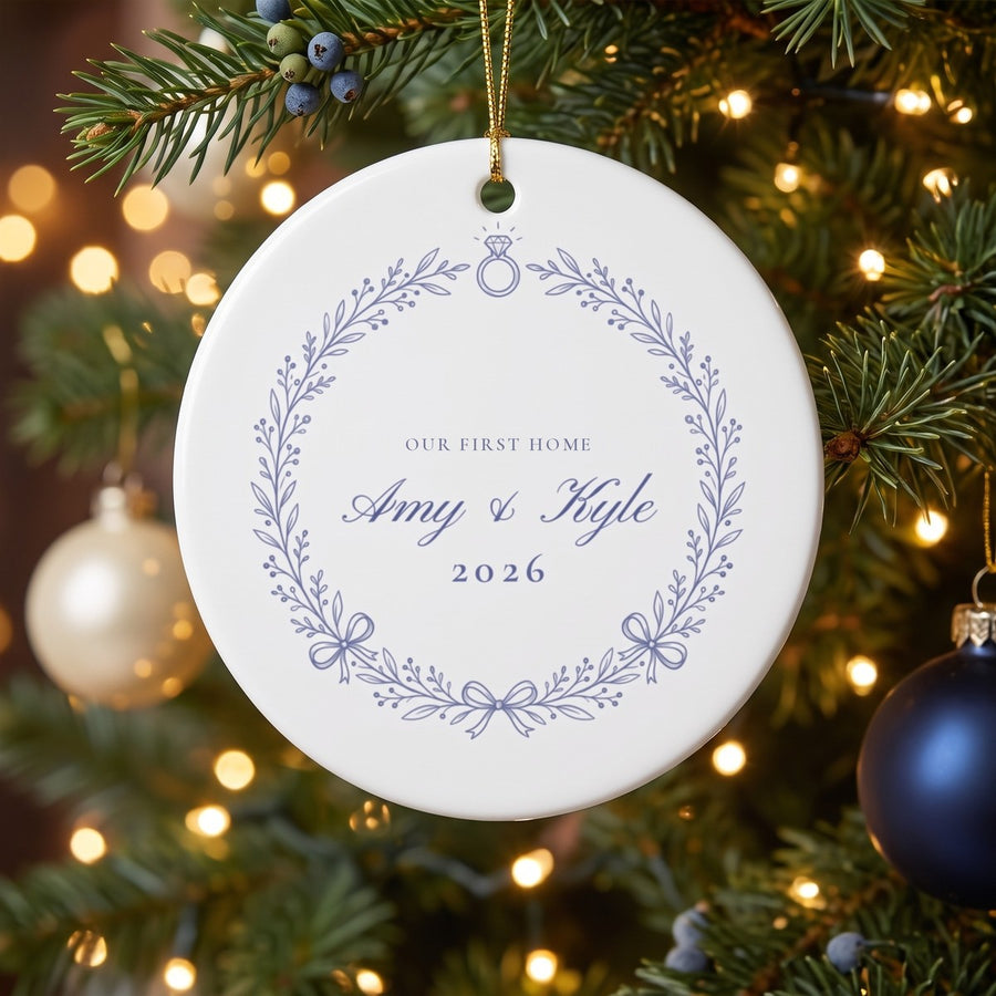 Our First Home personalized ceramic ornament with botanical wreath, names and year, hanging on a Christmas tree