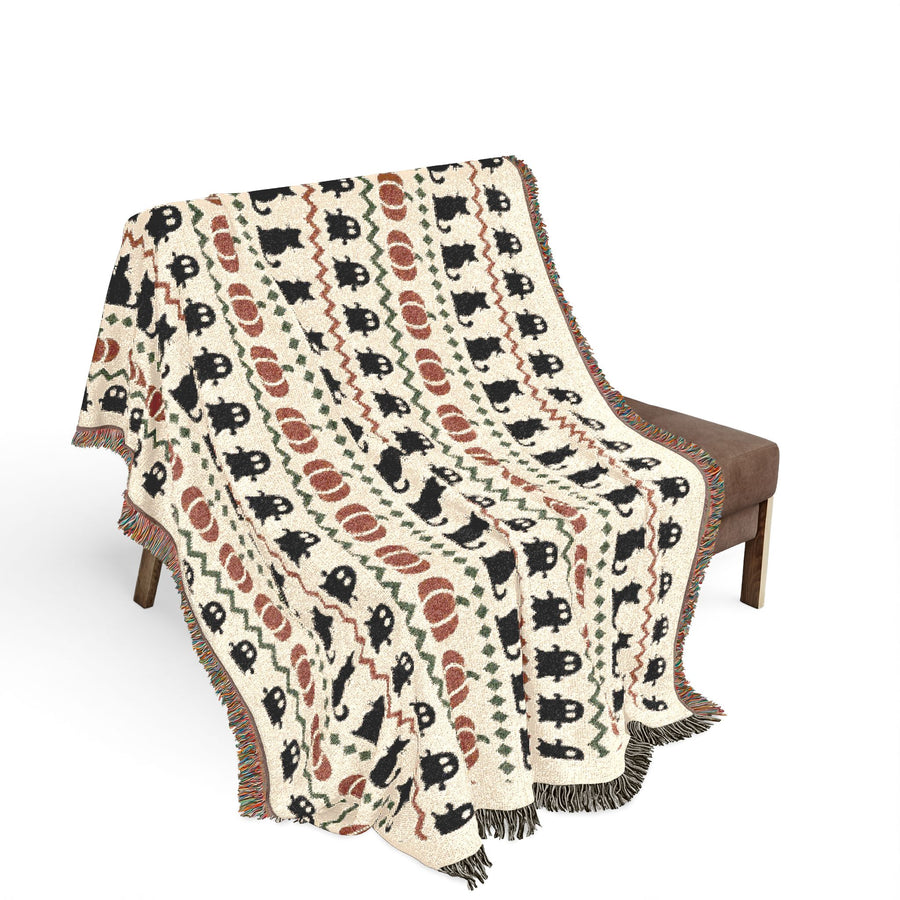 Ghost and black cat woven blanket folded, showing the fringed cotton edge