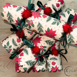 Red and green Christmas crackers laid along a festive dinner table