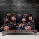 Skull woven blanket draped over a grey sofa, gothic floral cotton throw
