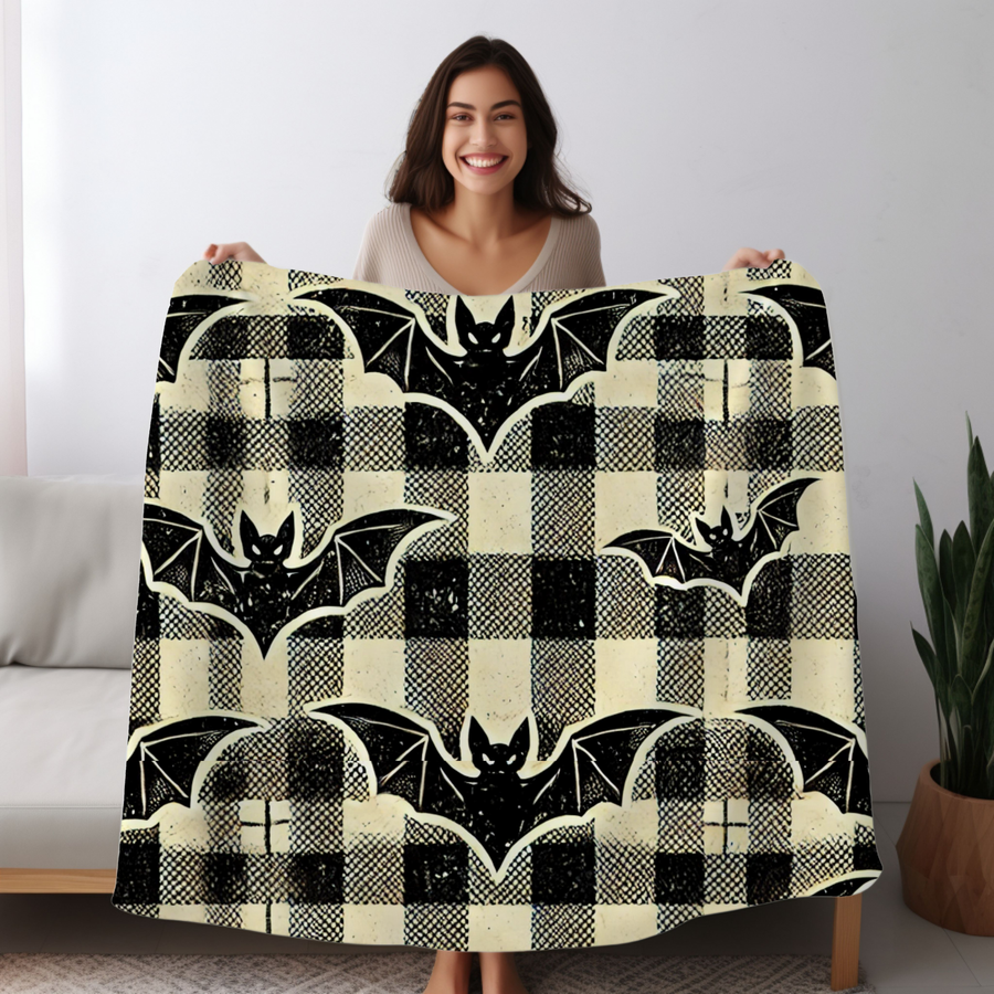 Woman holding the bat plaid Halloween fleece blanket open, black bats on a cream and black tartan check