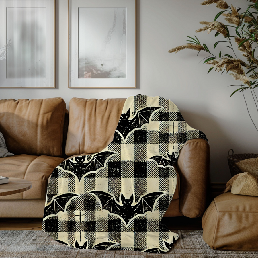 Bat plaid Halloween blanket draped over a tan leather sofa in a bright living room