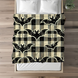 Bat plaid fleece blanket laid across the foot of a made bed with white pillows