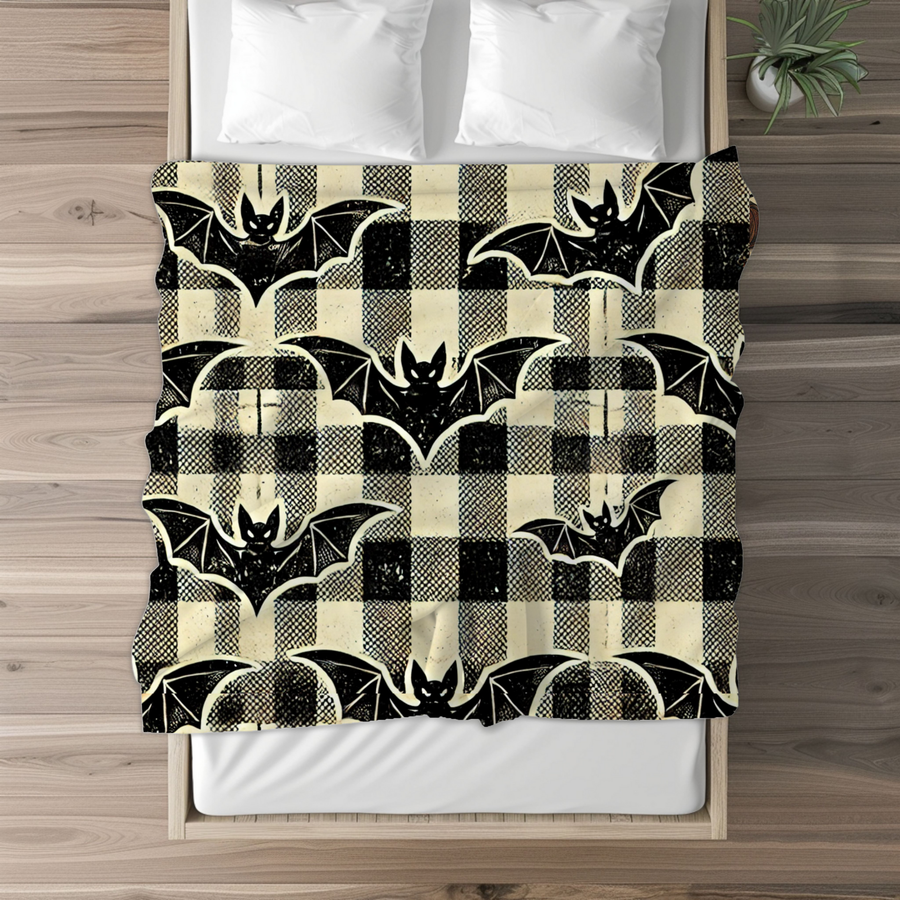 Bat plaid fleece blanket laid across the foot of a made bed with white pillows