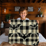 Child holding up the bat plaid Halloween blanket in a wood panelled bedroom