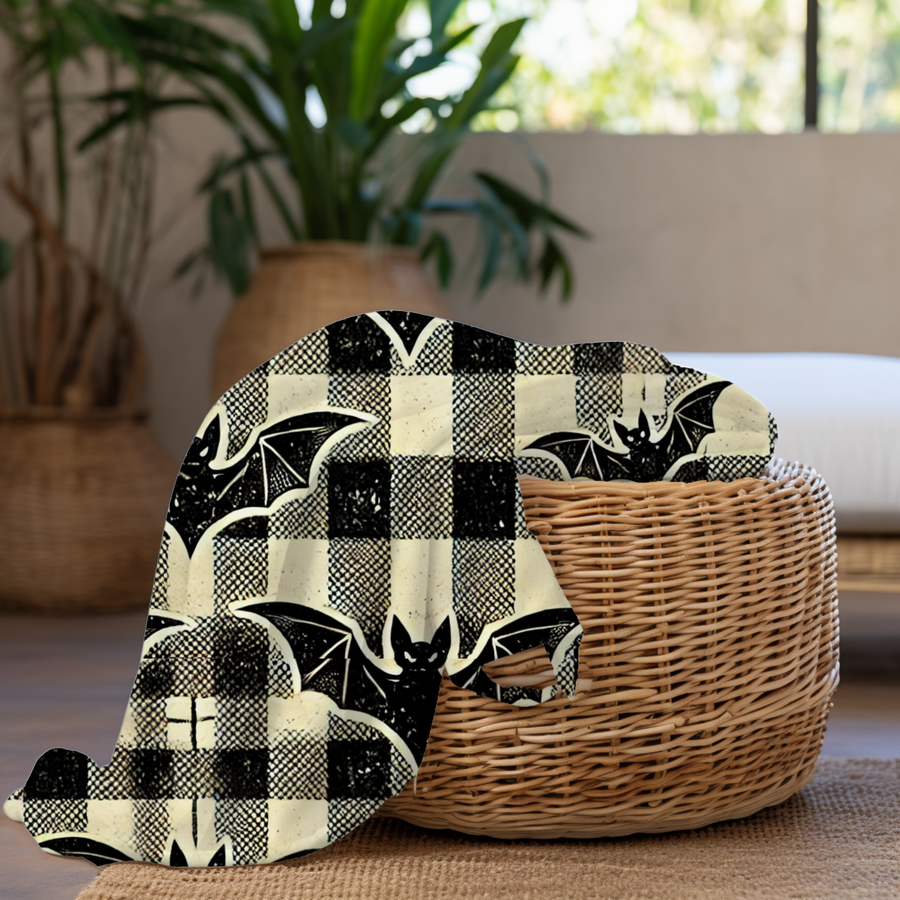 Bat plaid fleece blanket folded over a wicker basket beside houseplants