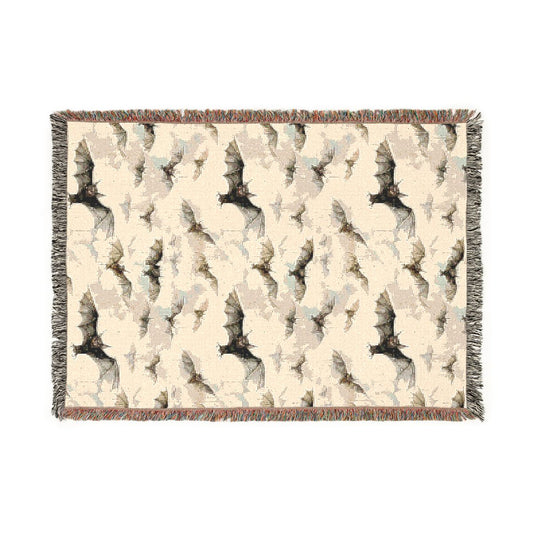 Bat woven blanket laid flat, cream cotton jacquard with a pattern of black bats and fringed edges
