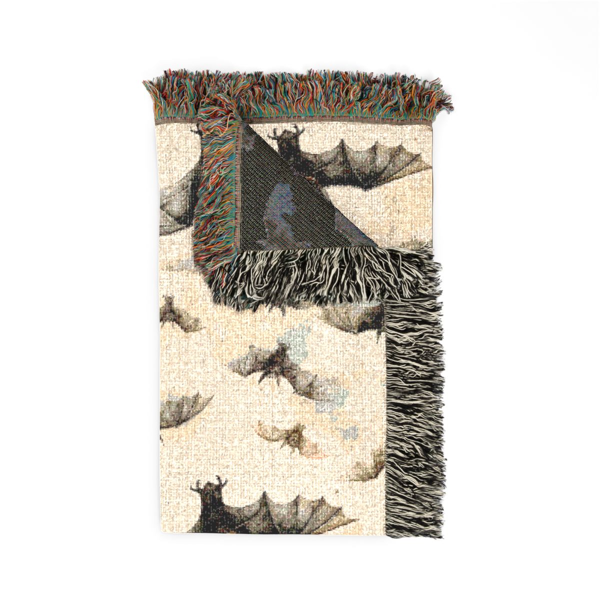 Bat woven blanket folded with one corner turned back to show the dark reverse side and fringe
