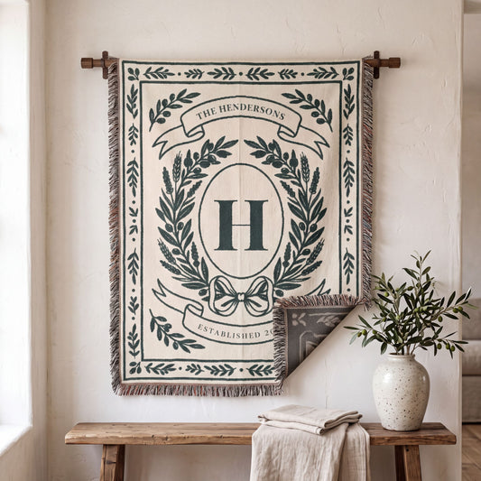 Personalized woven blanket with family crest and last name hung on a living room wall, corner folded to show the reverse