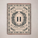 Personalized woven blanket with family crest and last name hanging on a wall