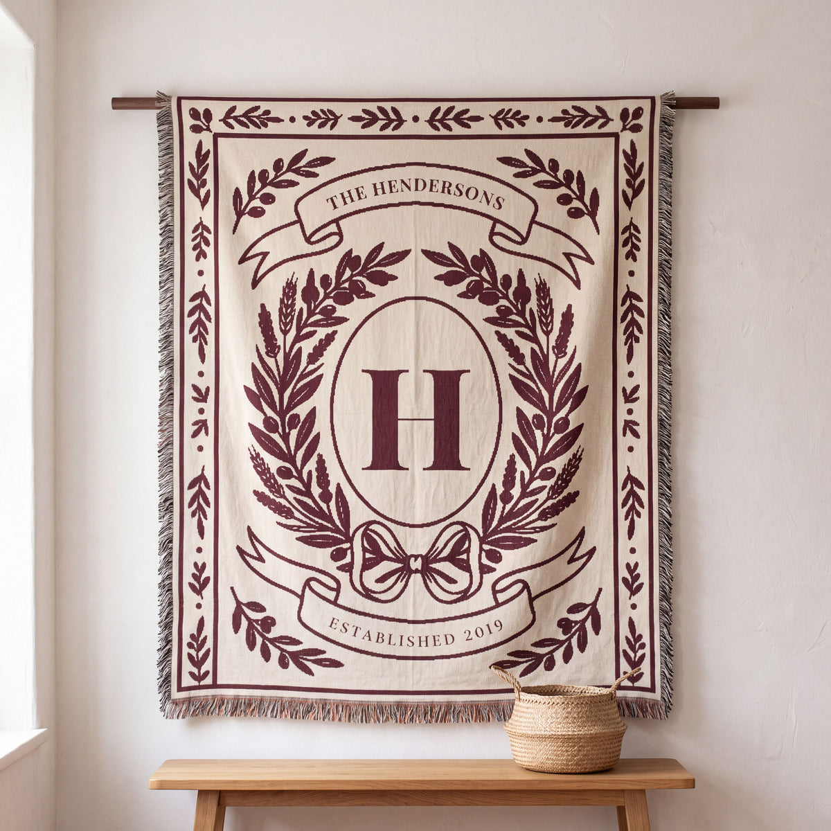 Burgundy personalized family crest woven blanket hanging on a wall