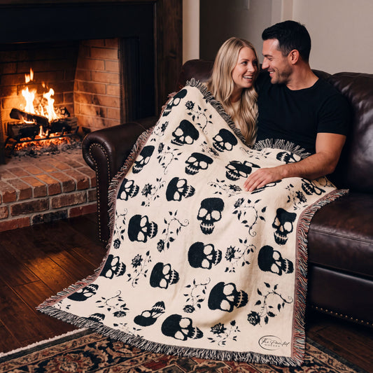 Couple by the fireplace under the black skull and roses woven blanket
