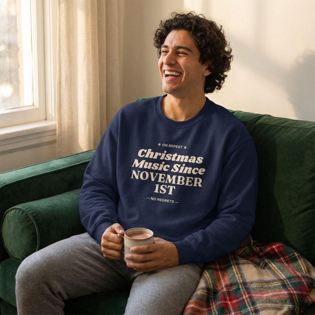 Man laughing on a green sofa with cocoa in the Navy Christmas Music Since November 1st crewneck