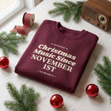 Maroon Christmas music sweatshirt folded on a pine table with fir sprigs, red ornaments and a vintage radio