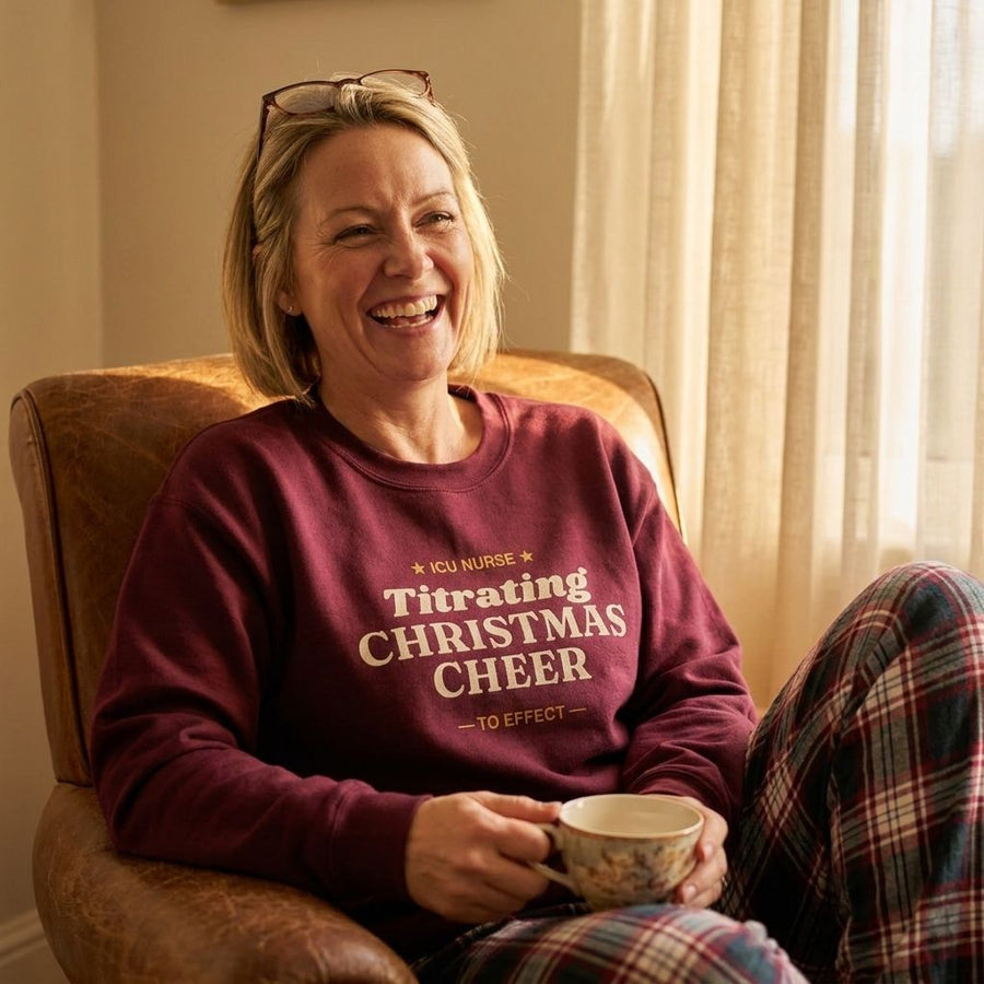 Woman laughing in an armchair with tea in the Maroon ICU nurse Christmas sweatshirt