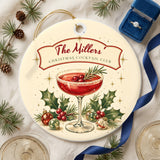 Christmas Cocktail Club ceramic ornament on linen with pine, coupe glasses and a navy ribbon