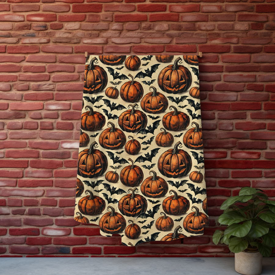 Pumpkin and bat Halloween blanket hung against a red brick wall