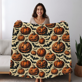 Woman holding the pumpkin and bat blanket wide so the full Halloween print is visible