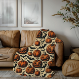 Pumpkin and bat Halloween blanket draped over a tan leather sofa in a living room