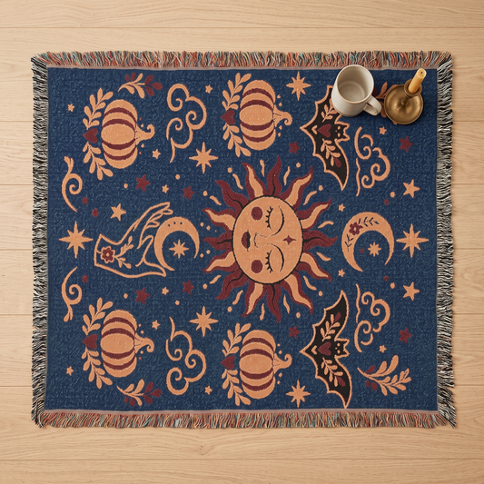 Overhead flatlay of the celestial sun and moon woven blanket on light oak, showing the full navy and apricot design with multicoloured fringe
