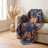 Whimsigoth celestial woven blanket draped over an oatmeal linen sofa in a bright cream room