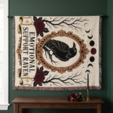 Raven woven blanket hung on a forest green wall as a gothic tarot style tapestry