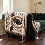 Emotional Support Raven woven throw draped over a deep green velvet sofa in a gothic styled room