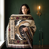Woman wrapped in The Overlord black cat tarot woven blanket, cream cotton with a crowned black cat, gold crescent moon and oxblood roses