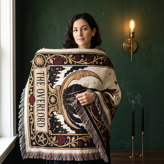Woman wrapped in The Overlord black cat tarot woven blanket, cream cotton with a crowned black cat, gold crescent moon and oxblood roses