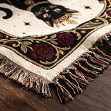 Close up of the woven cotton weave, gold scrollwork border and knotted fringe on the black cat tarot blanket