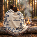 Couple wrapped in a personalized navy woven blanket by a campfire