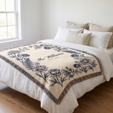 Navy family name woven blanket laid across a white linen bed