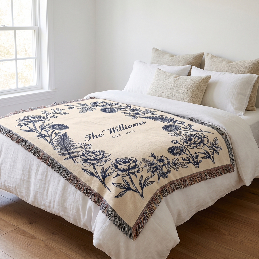 Navy family name woven blanket laid across a white linen bed
