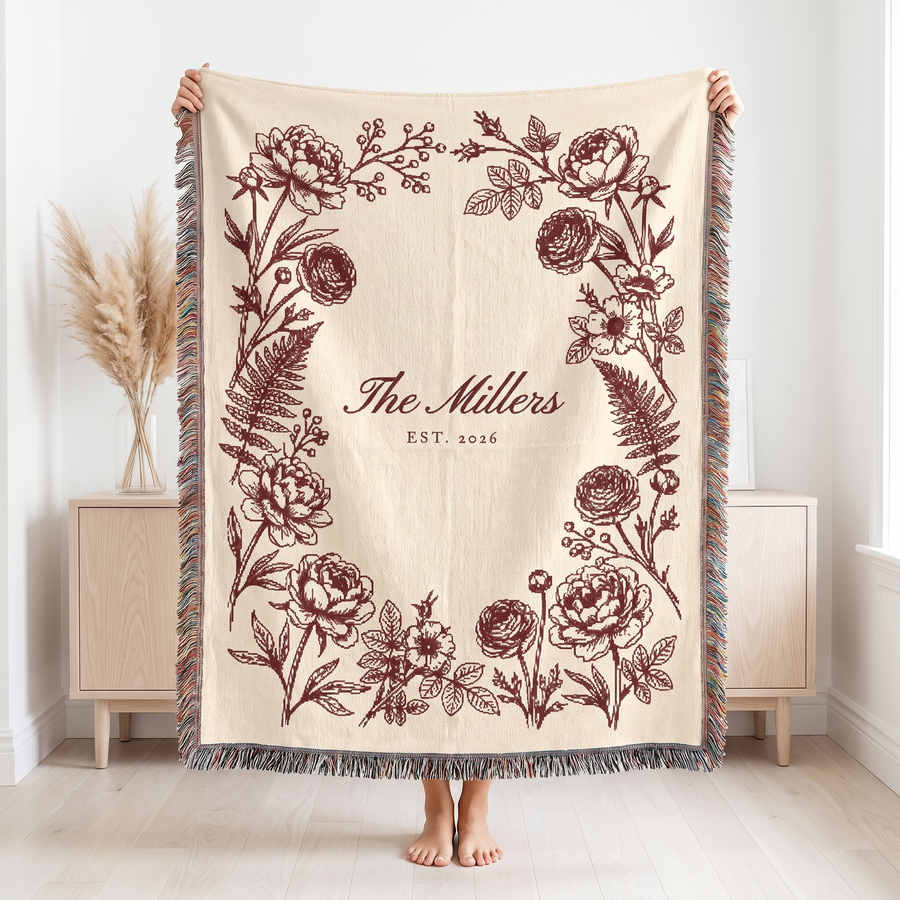 Burgundy family name woven blanket held up to show the 60 x 80 size