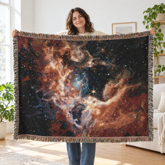 Woman holding up the nebula woven throw blanket to show the full James Webb telescope image