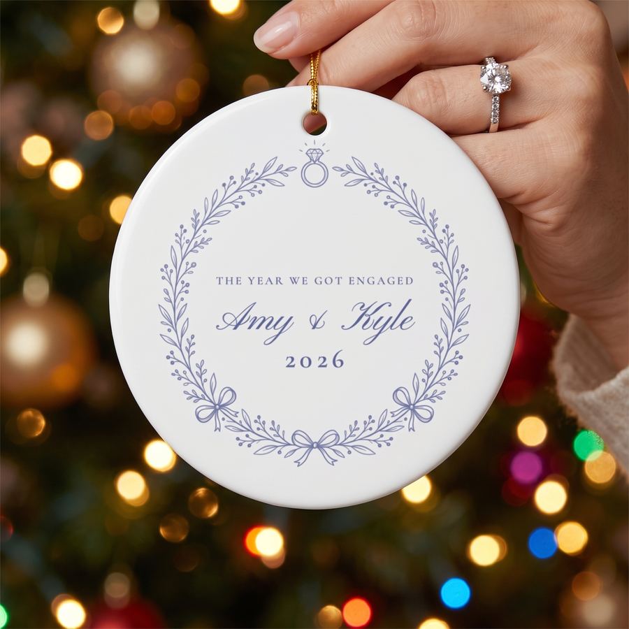 Hand with engagement ring holding the blue wreath engagement ornament