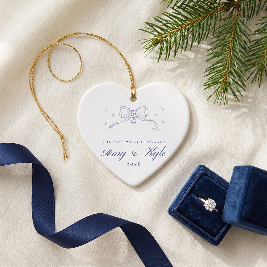 Heart ribbon bow engagement ornament on linen with pine, navy ribbon and an engagement ring box