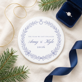 Blue wreath engagement ornament on linen with pine, navy ribbon and an engagement ring box