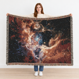 Woman holding up the NASA JWST Tarantula Nebula Woven Blanket to show its true 80 x 60 inch size