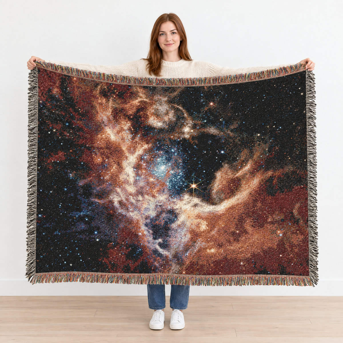 Woman holding up the NASA JWST Tarantula Nebula Woven Blanket to show its true 80 x 60 inch size