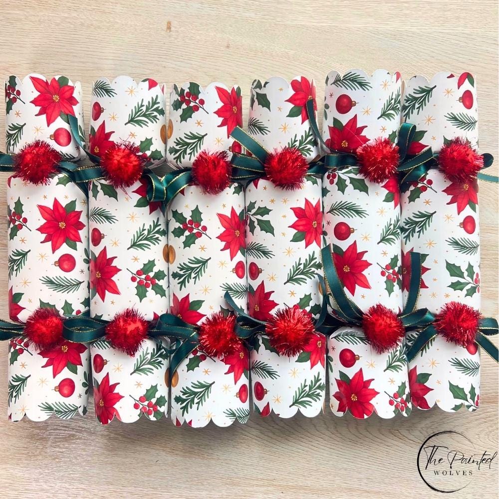 Six red poinsettia Christmas crackers in a row with green ribbon and red pom poms