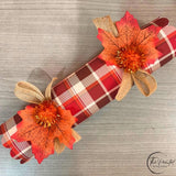 Single fall plaid cracker finished with an orange pom pom, burlap ties and a faux leaf